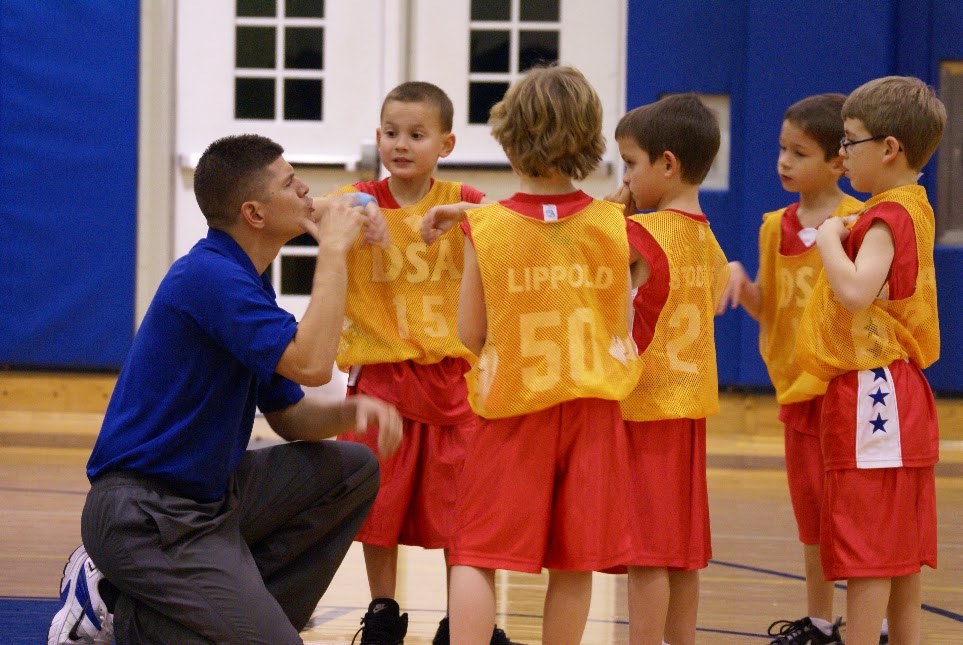 DSA founder kneeling to coach young basketball players